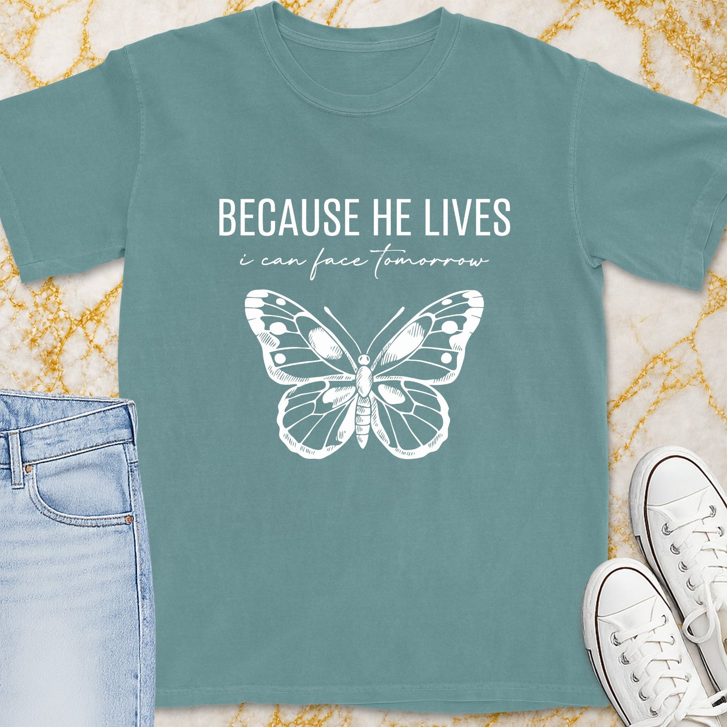 Teal t-shirt with white text "BECAUSE HE LIVES" and butterfly graphic.