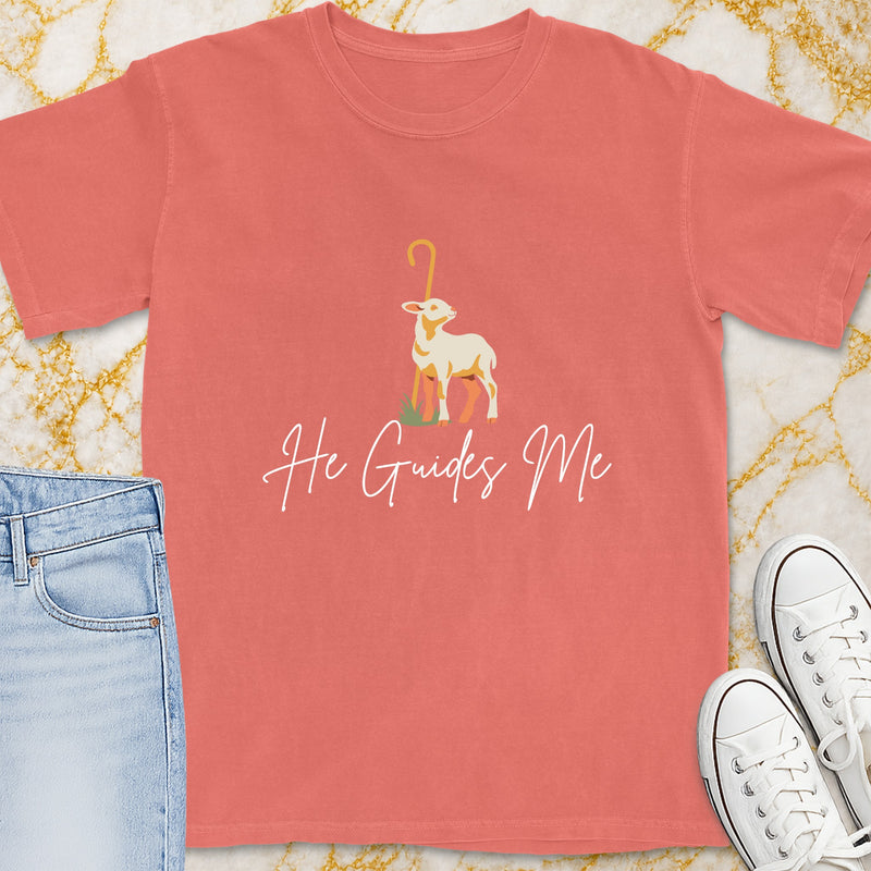 Coral t-shirt with a lamb graphic and "He Guides Me" text.