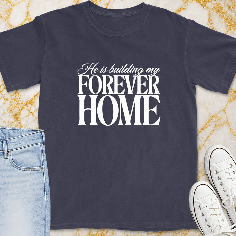 Dark t-shirt with white text "He is building my FOREVER HOME."