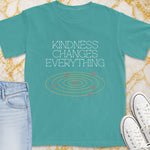 Teal t-shirt with "Kindness Changes Everything" and pink hearts in concentric circles.